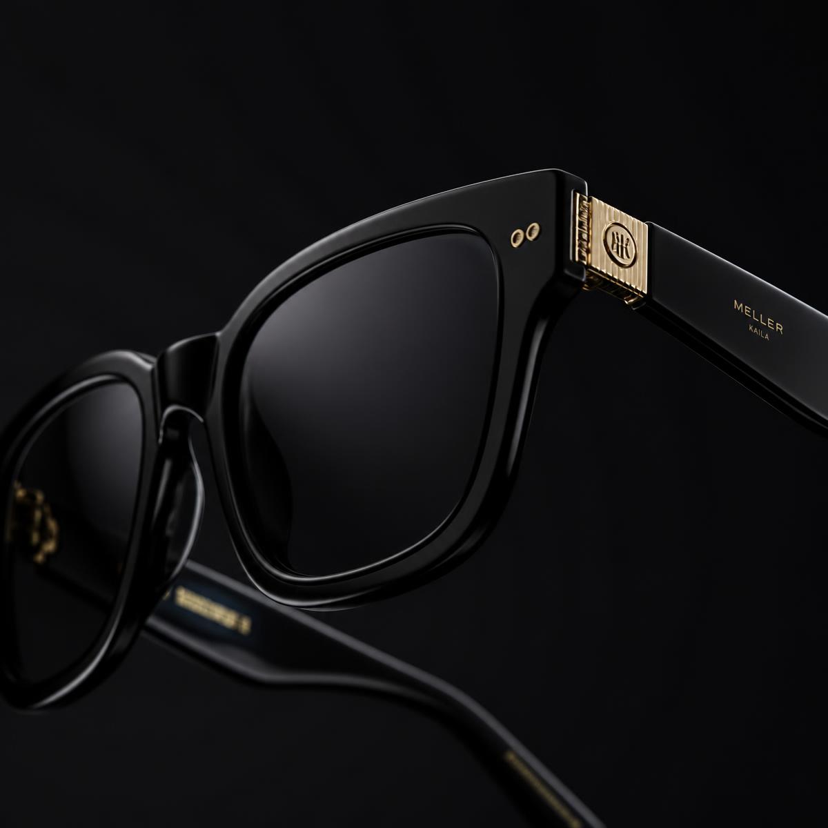 Close macro of a black acetate wayfarer frame with a gold hinge detail