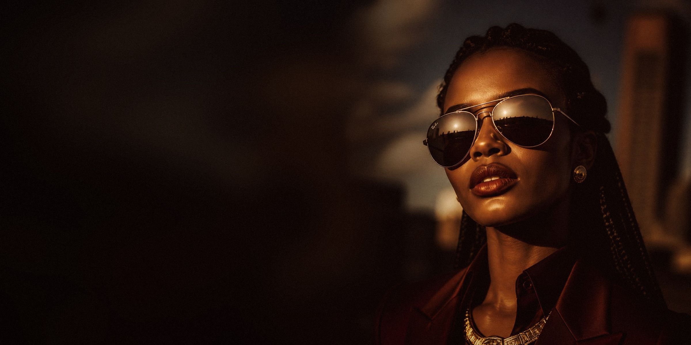 Model wearing gold aviator sunglasses in warm evening light